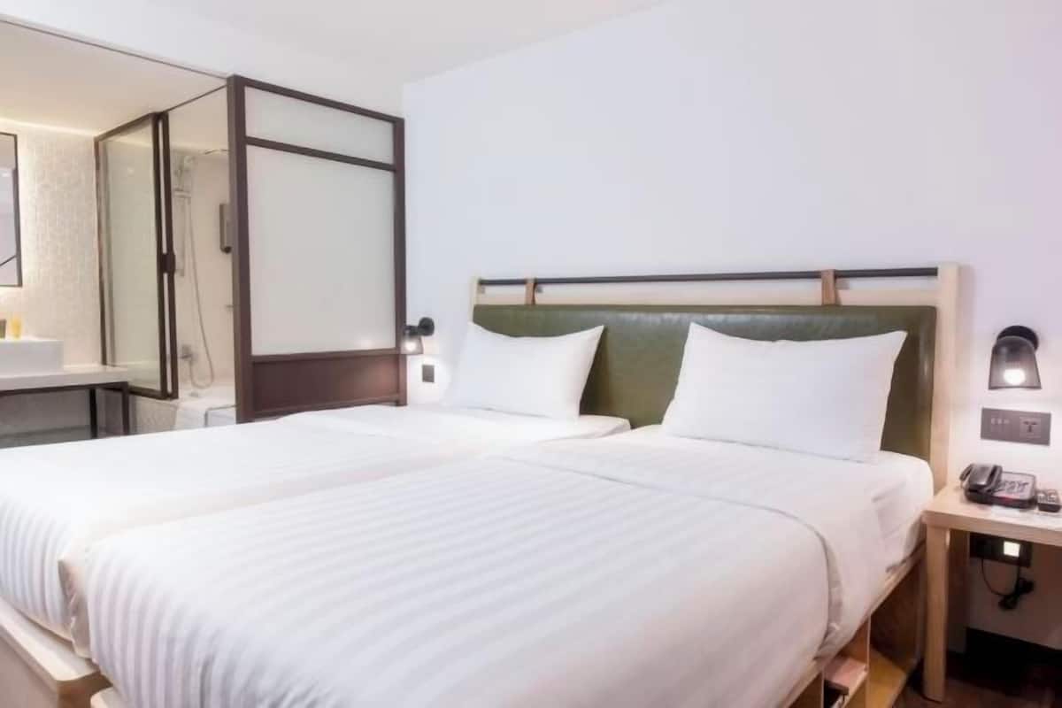 A hotel room with a bed, bedside table, lamp, and a mirror.