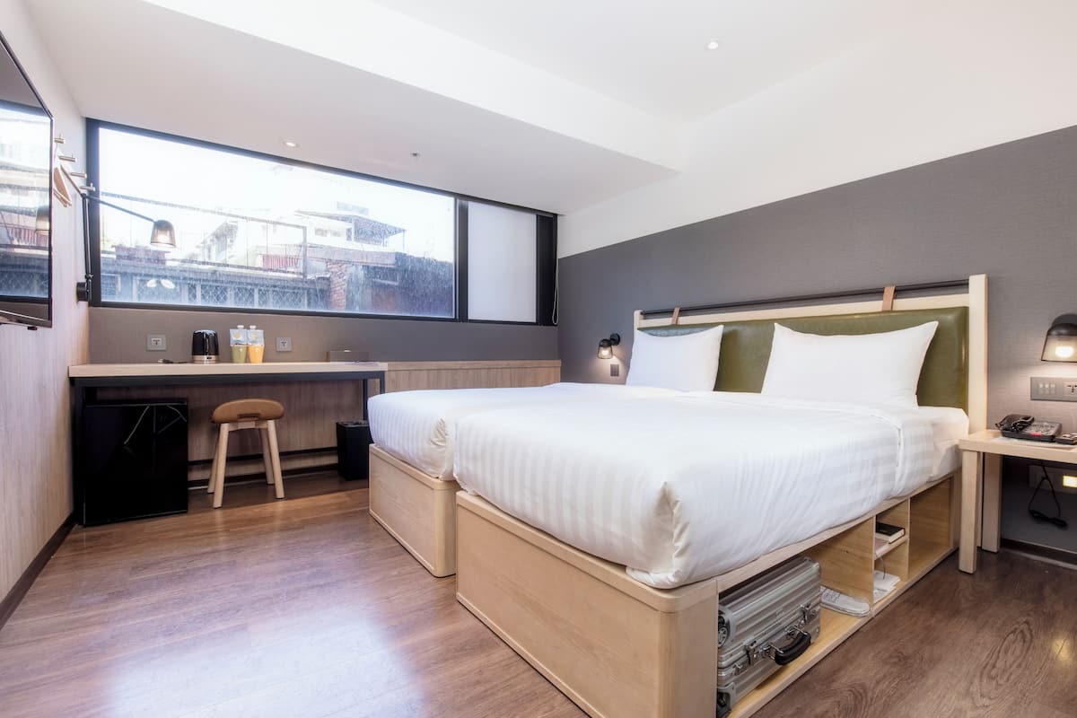 A modern hotel room with a large bed, a desk, and a window with a city view.