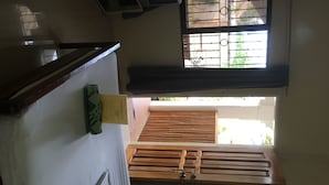 A room with a wooden bed, a window with metal bars, and a ceiling fan. - John Verhel Homes and Island Tours (Panglao)