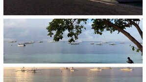 A beach with people walking, boats in the water, and a tree with leaves. - John Verhel Homes and Island Tours (Panglao)
