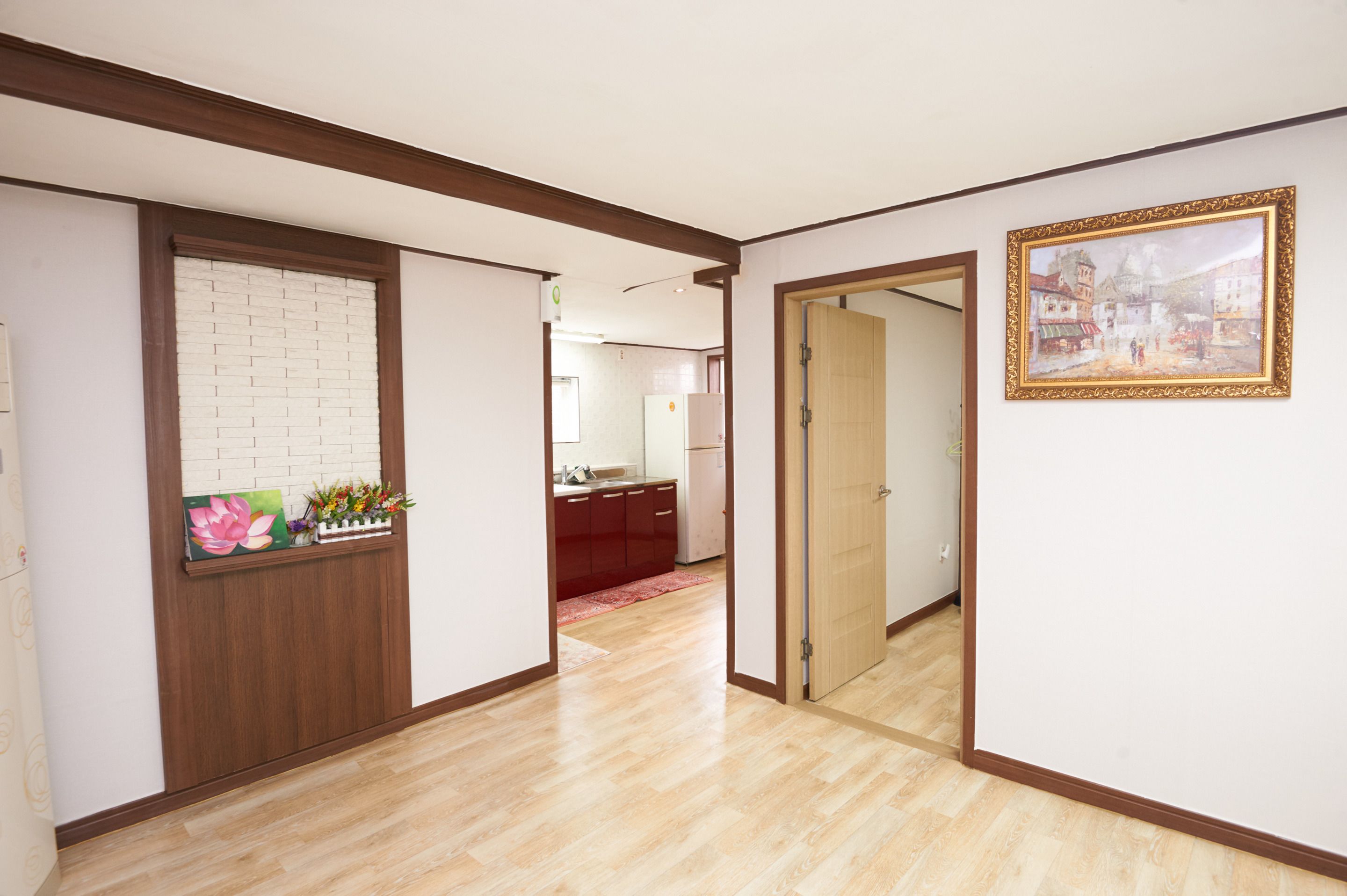 A hallway with wooden trim, a white brick wall, a red rug, and a framed picture on the wall.