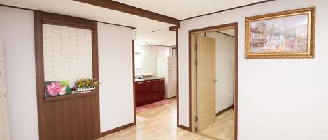 A hallway with wooden trim, a white brick wall, a red rug, and a framed picture on the wall.