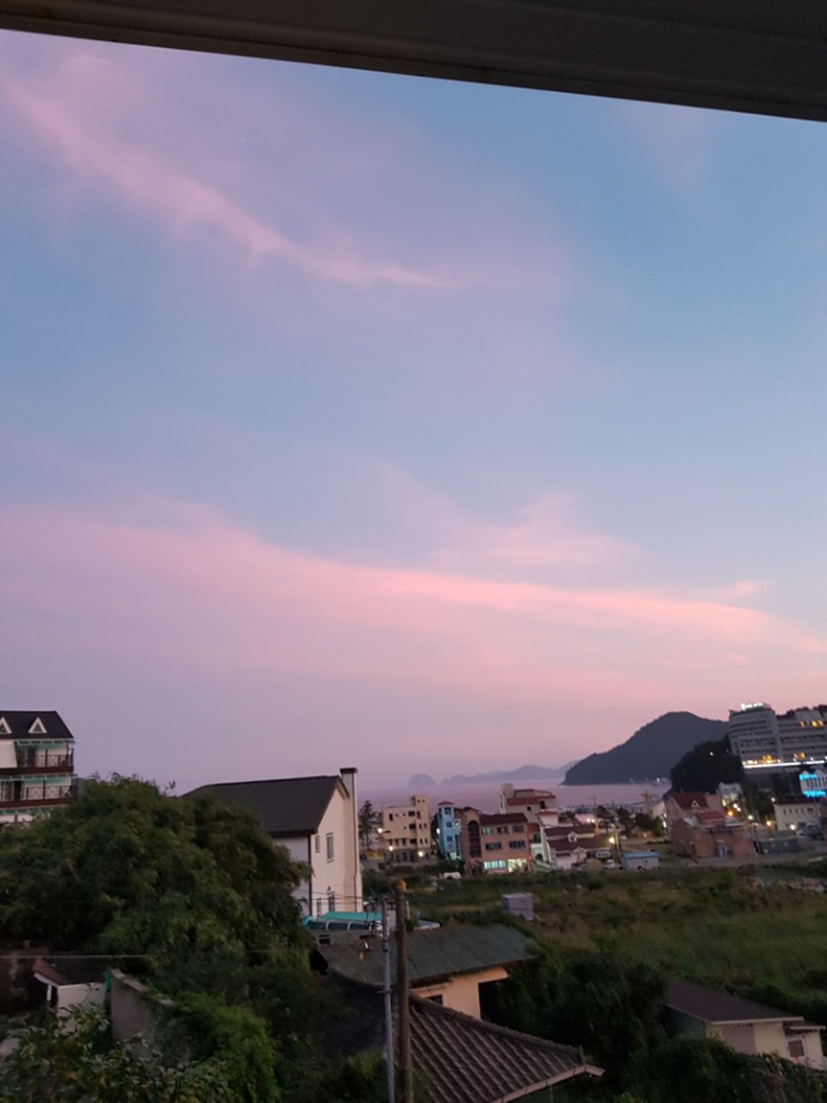 Blick auf eine Küstenstadt mit Gebäuden, einer Kirche und einem Berg im Hintergrund.