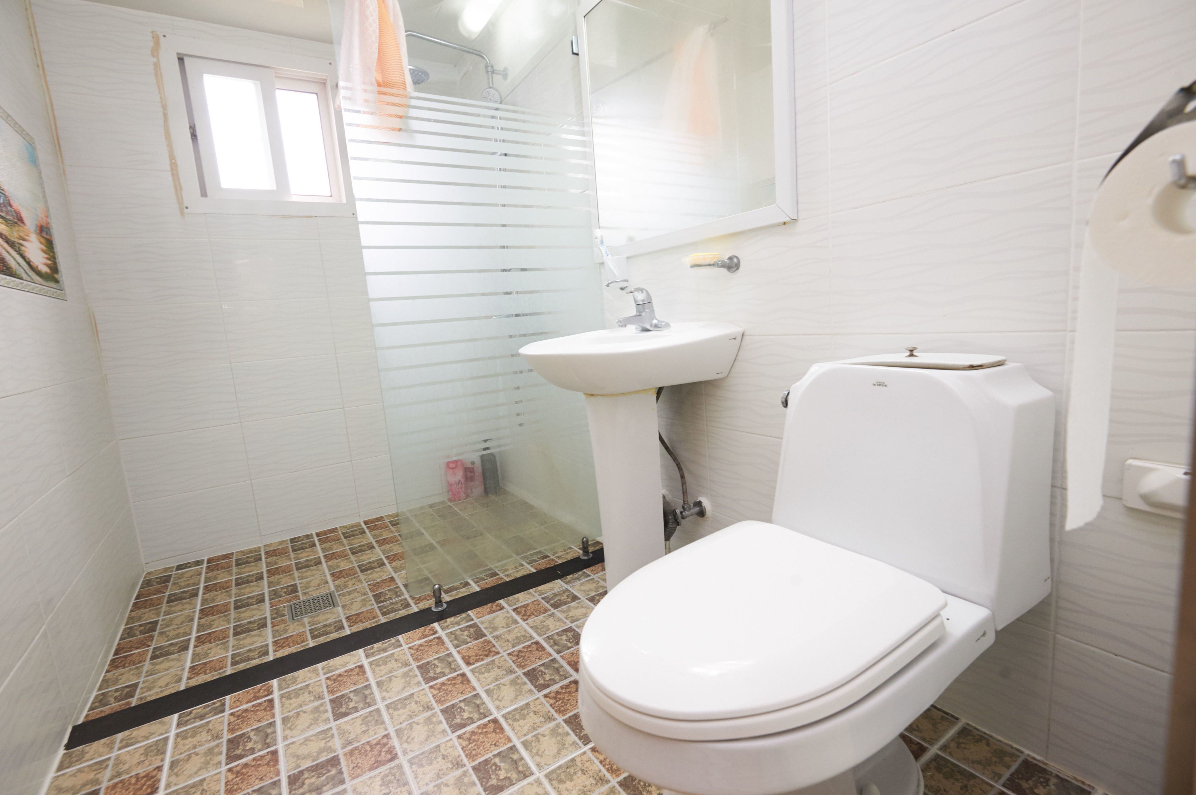 Un baño con inodoro, lavamanos y zona de ducha.