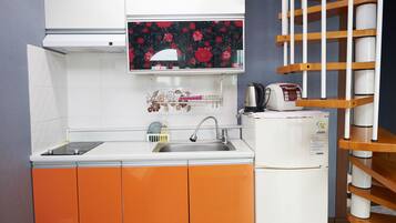 Cocina compacta con lavamanos, cafetera y refrigerador.
