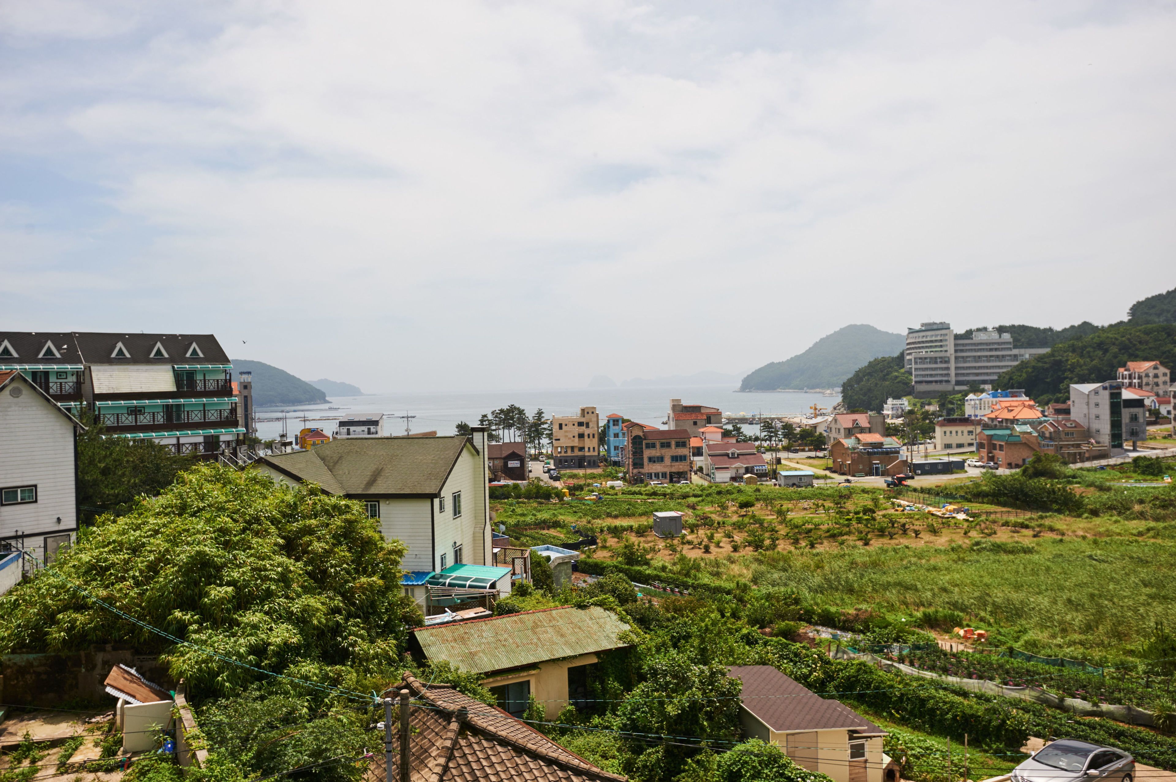 A coastal town with a mix of residential and commercial buildings, including a prominent hotel with a green roof and a view of the sea.