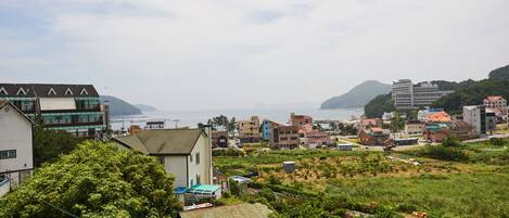 A coastal town with a mix of residential and commercial buildings, including a prominent hotel with a green roof and a view of the sea.