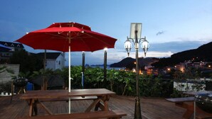 A wooden deck with a picnic table and a red umbrella. - Sand Beach Pension (Geoje)
