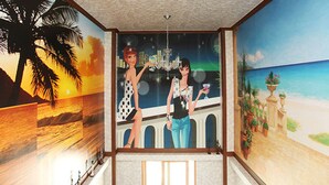 A room with a mural of a sunset, palm trees, and a beach scene. - Sand Beach Pension (Geoje)