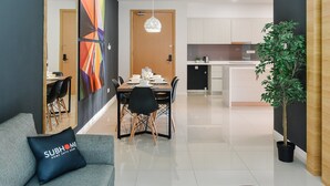A modern living room with a sofa, coffee table, and a dining area with chairs and a table. - Suasana Suites by Subhome (Johor Bahru)