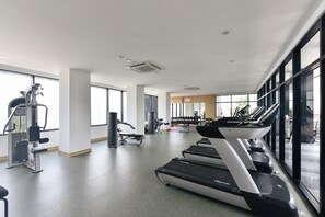 Un gimnasio con cintas de correr, máquinas de pesas y un amplio ventanal.