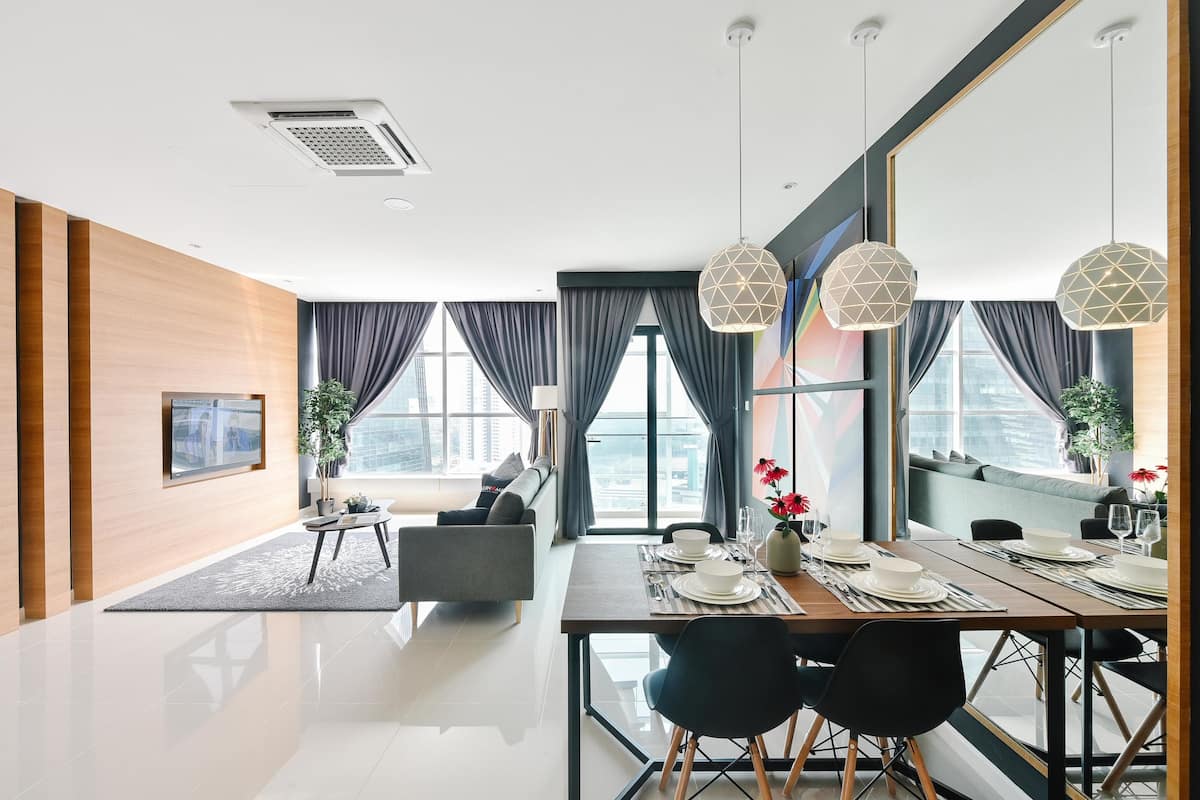 A modern dining area with a large table set for four, a sofa, and a city view through large windows.