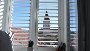A window with white shutters, a small potted plant, and a book on the windowsill. - Optimist Makarska Town Center (Makarska)