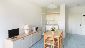 Eine moderne Küche mit weißen Schränken, einem Holztisch und einem Fernseher auf einem Schrank.