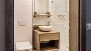 A modern bathroom with a wooden vanity, a white sink, and a glass shower enclosure. - Liebig Hotel (Giessen)