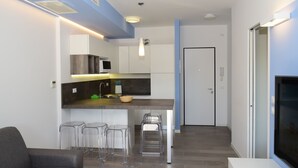 A modern kitchen with a central island, bar stools, and a dining area with a sofa.