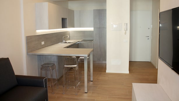 A modern kitchen with a central island, bar stools, and a built-in oven.