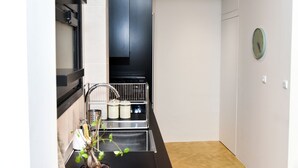 A compact kitchen with a black cabinet, stainless steel sink, and a small potted plant.