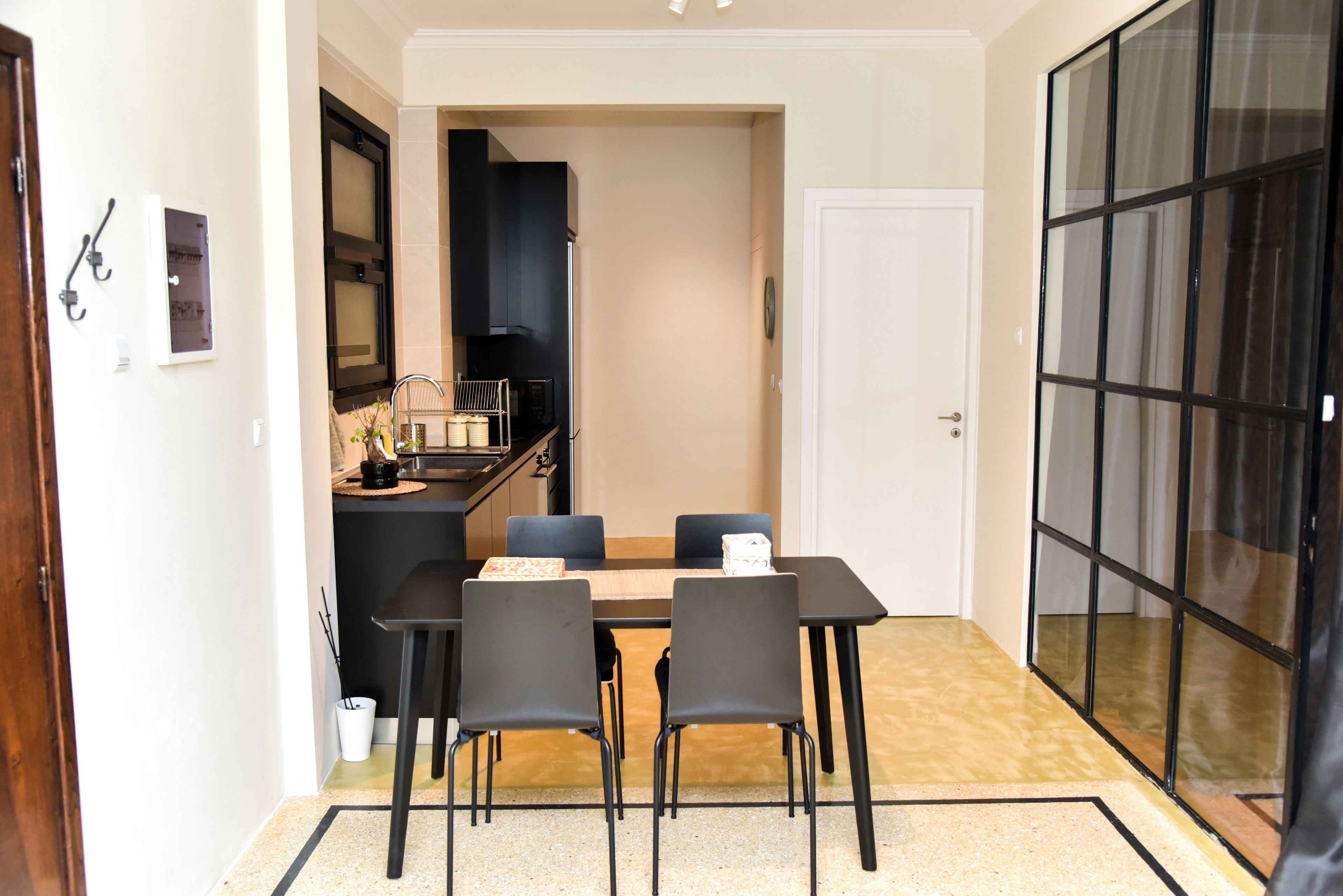 A compact dining area with a table and four chairs, a kitchen with a stove and cabinets, and a sliding glass door leading to a balcony.