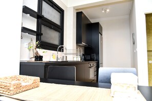 A modern kitchen with black cabinets, a microwave, and a sink. There is a dining area with a table and chairs. - Central apartment at Echarxia 2 beds for 4 pers  (Athens)