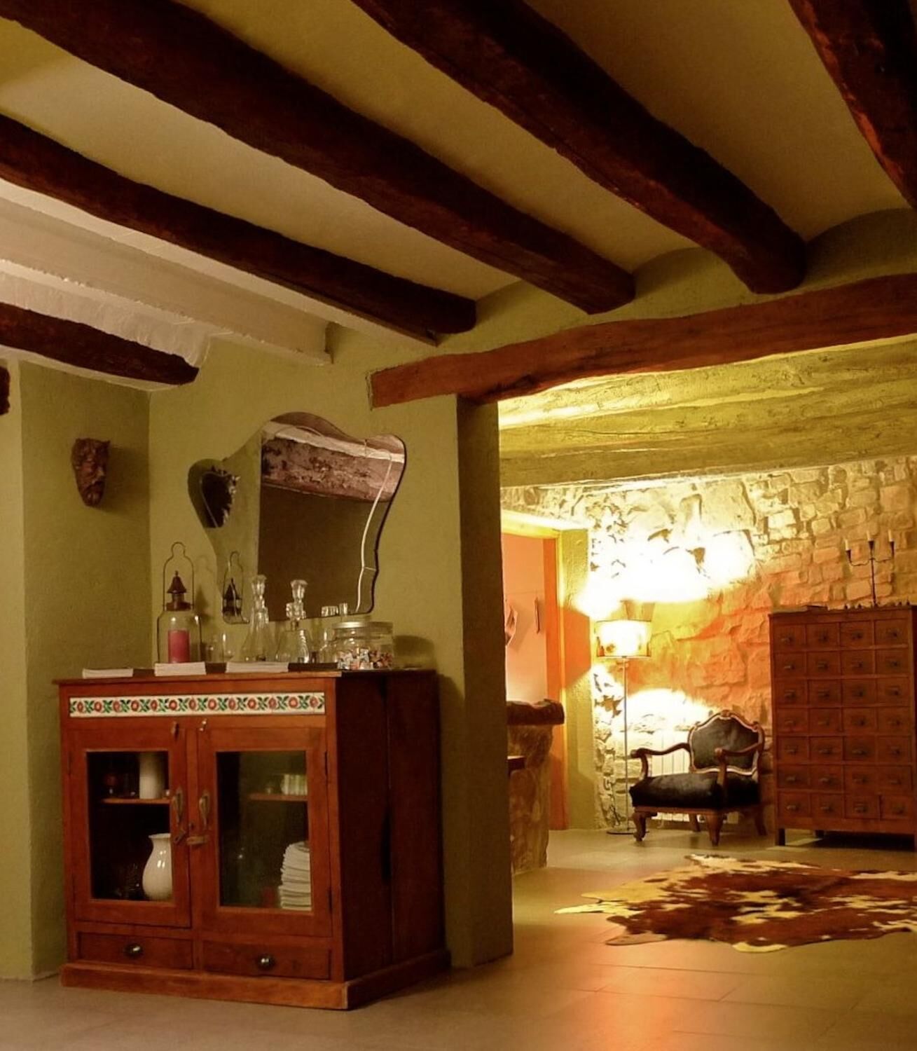 A room with a wooden cabinet, a stone wall, and a lamp.