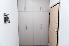 A neutral-toned wardrobe with four doors, a small decorative sign on the wall, and a wooden door to the right. - Modern  Apartment at Exarchia 1 bed 2 pers  (Athens)