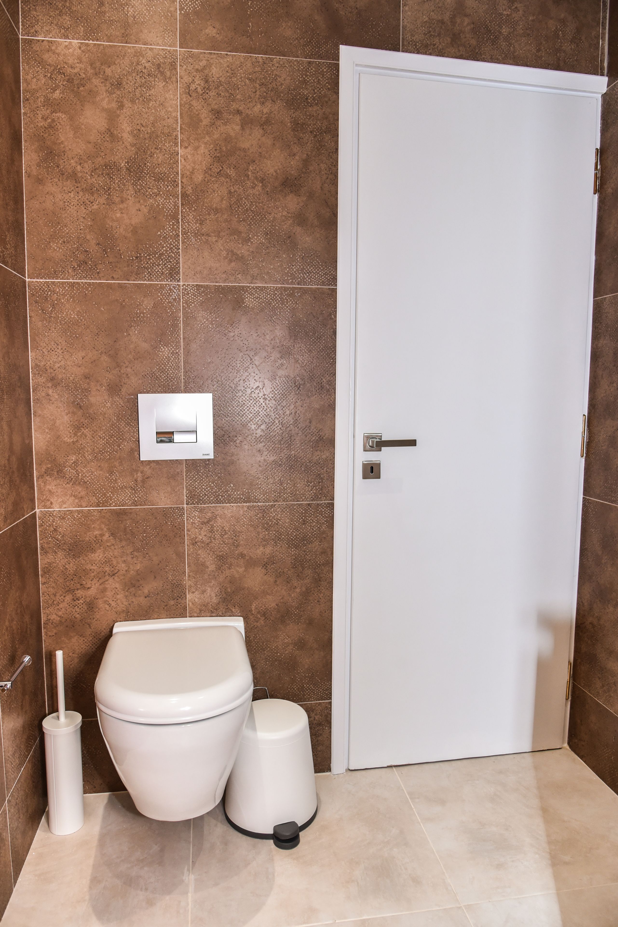 A bathroom with a toilet, bidet, and a white door.