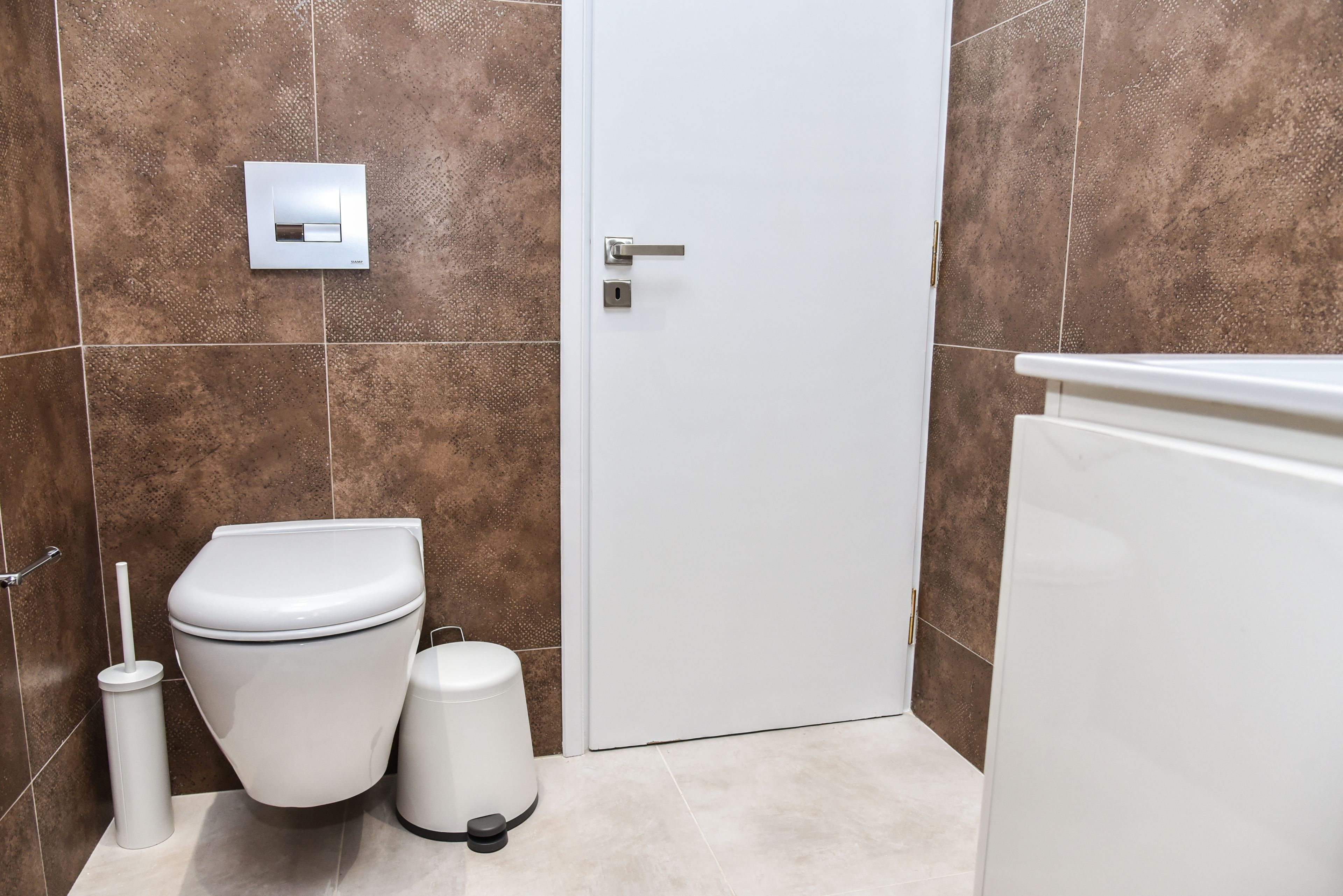 Une salle de bain avec des toilettes blanches, un bidet et une poubelle.