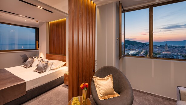 Un dormitorio moderno con una cama grande, vistas a un paisaje urbano y un separador de madera.