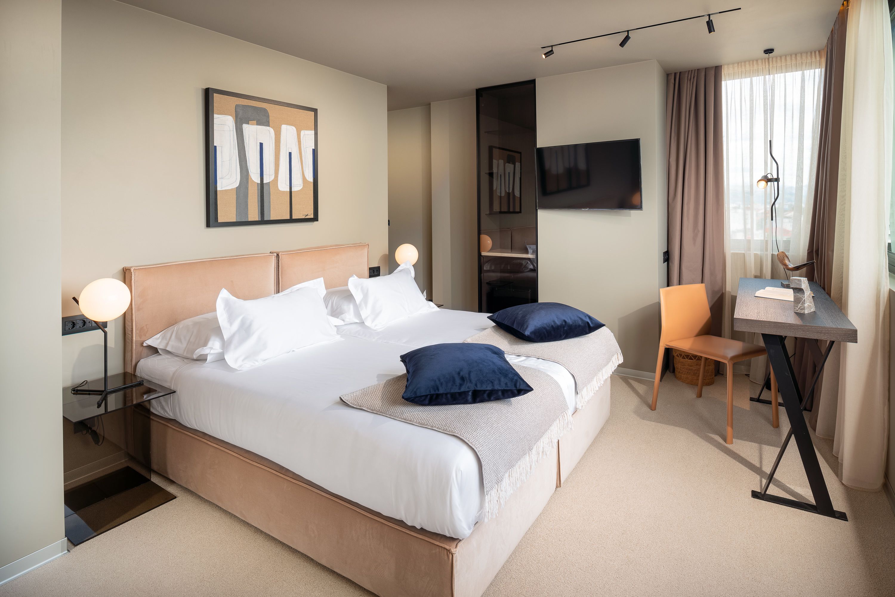 Una habitación de hotel moderna con una cama grande, un escritorio y un televisor.