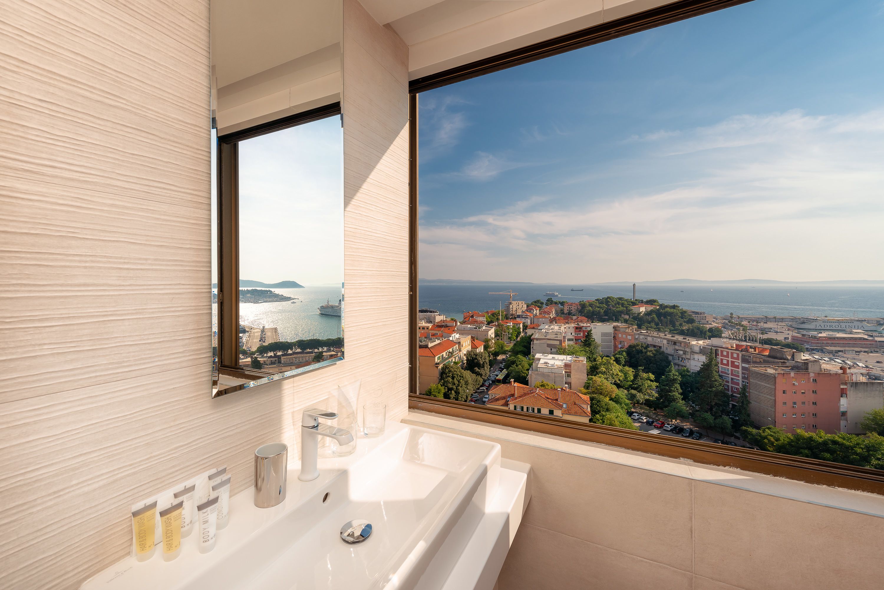 A modern bathroom with a large window offering a city view.