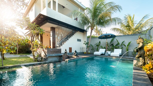 A swimming pool with a staircase leading to a balcony, surrounded by palm trees and a statue. - Liam Private Villa (Sukawati)