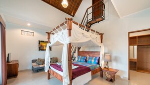 A four-poster canopy bed with a wooden headboard, a bedside table with a lamp, and a small wooden cabinet. - Liam Private Villa (Sukawati)