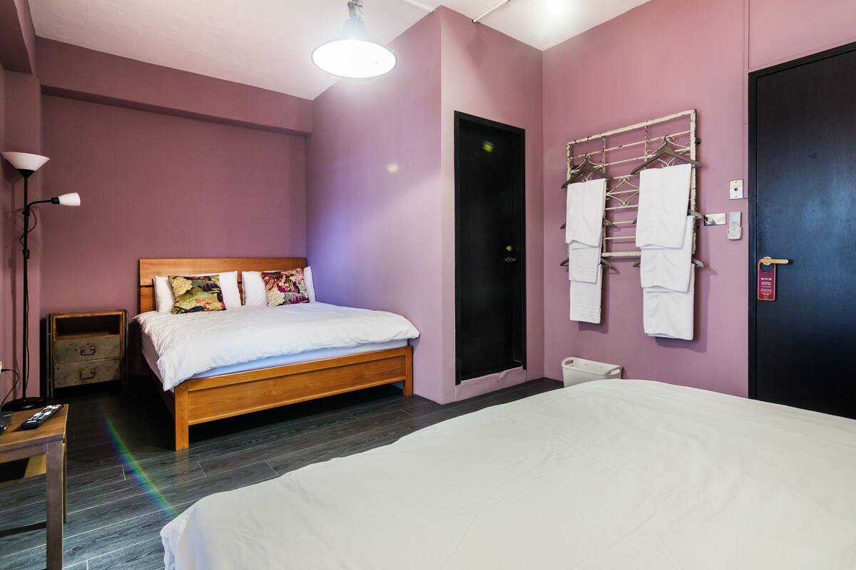 Een slaapkamer met een houten bed, een nachtkastje, een wandrek voor handdoeken en een deur met een greep.