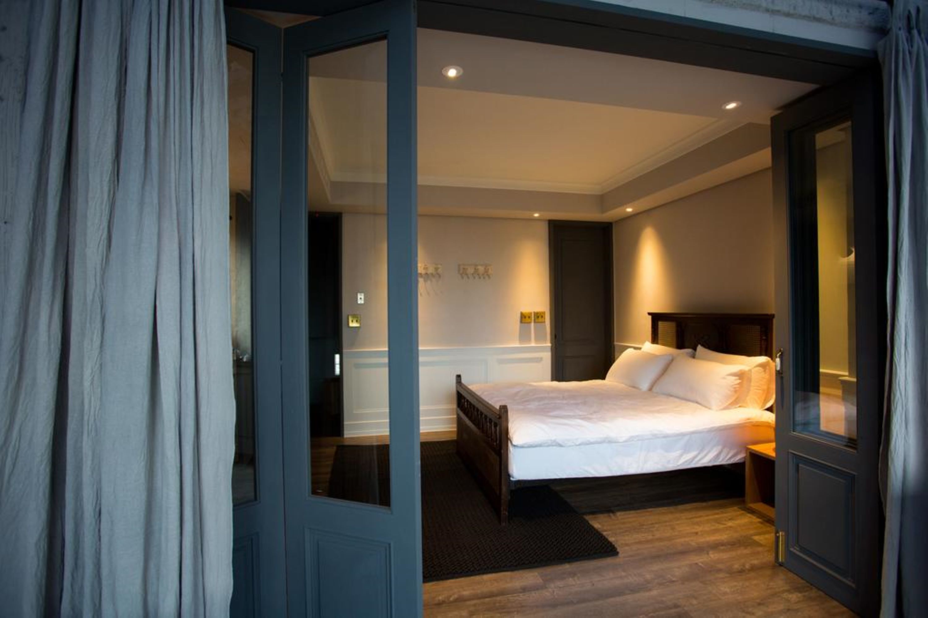 A bedroom with a bed, a nightstand, and a door leading to another room.