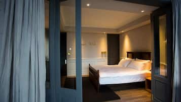 A bedroom with a bed, a nightstand, and a door leading to another room.