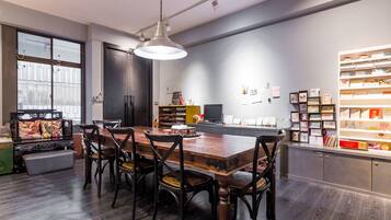 A modern kitchen with a wooden dining table, dark wood flooring, and a large window.