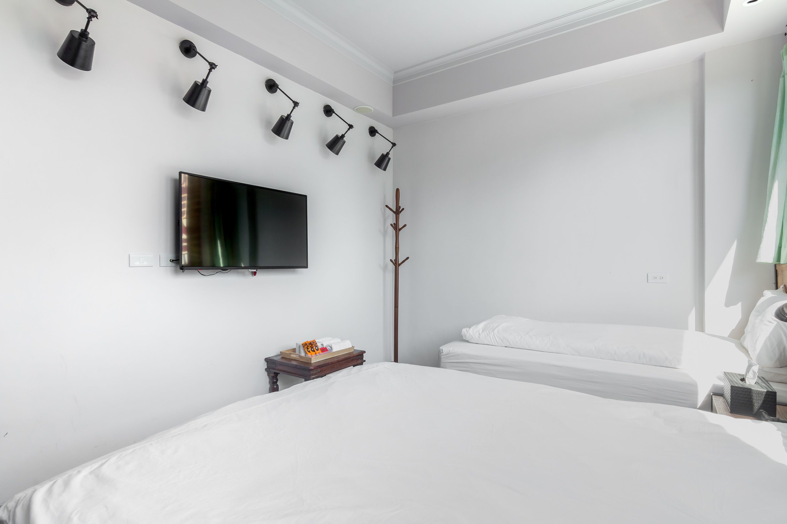 Une chambre d’hôtel dotée d’un grand lit, d’un téléviseur à écran plat fixé au mur, d’une table de chevet avec une lampe et d’un porte-manteau.