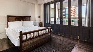 Quarto com uma cama grande, porta de madeira escura e vista para o exterior.