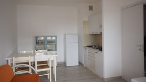 A compact kitchen with a dining table and chairs, a refrigerator, and a sink.