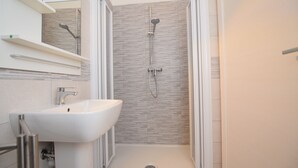 A modern bathroom with a shower, a sink, and a mirror.