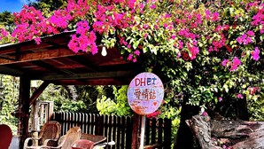 A bicycle parked under a wooden pergola with a sign reading 'DHET Love Station.' - Fong Chou Cottage (Sanyi)