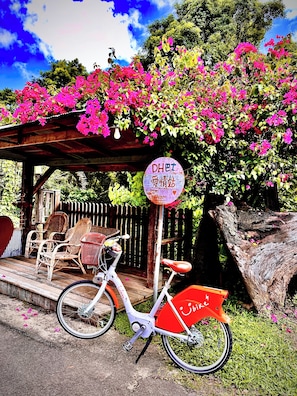 A bicycle parked under a wooden pergola with a sign reading 'DHET Love Station.' - Fong Chou Cottage (Sanyi)