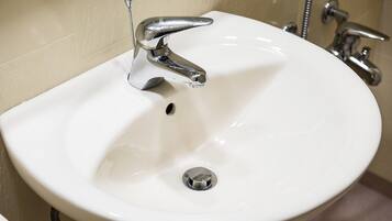 Un lavabo de salle de bain blanc, doté d’un robinet chromé et d’un drain.