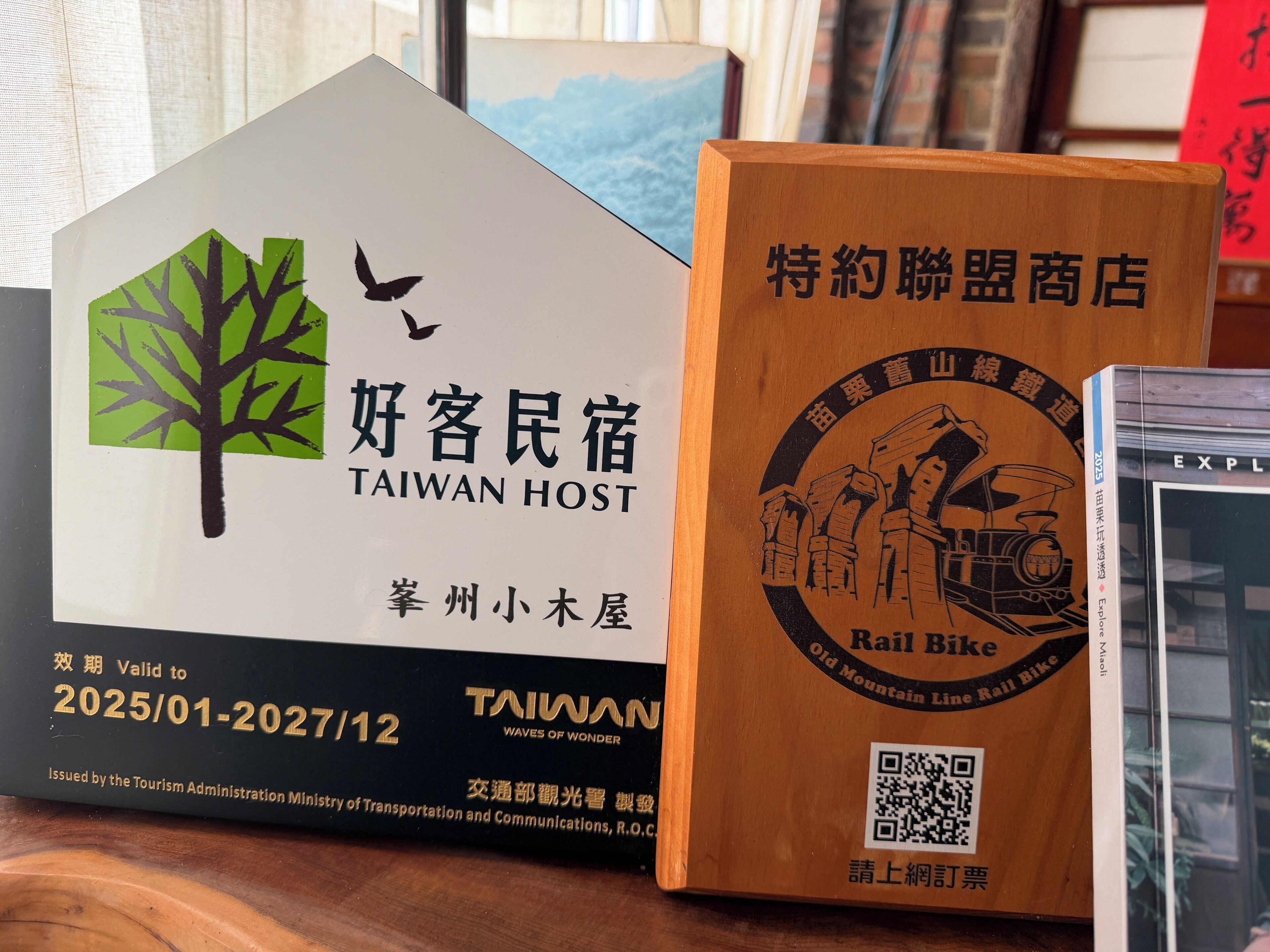 A Taiwan Host sign with a tree and bird logo, a QR code, and a date range.
