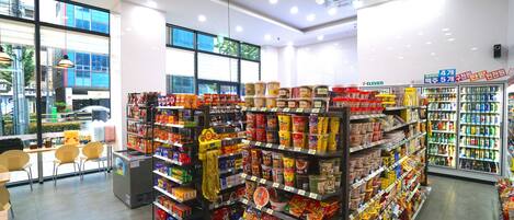 Un supermercado bien iluminado con estantes llenos de diversos productos alimenticios y una sección refrigerada a la derecha.