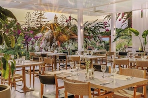 A restaurant with multiple tables and chairs, each set with cutlery and glasses. - Nissi Beach Resort (Ayia Napa)