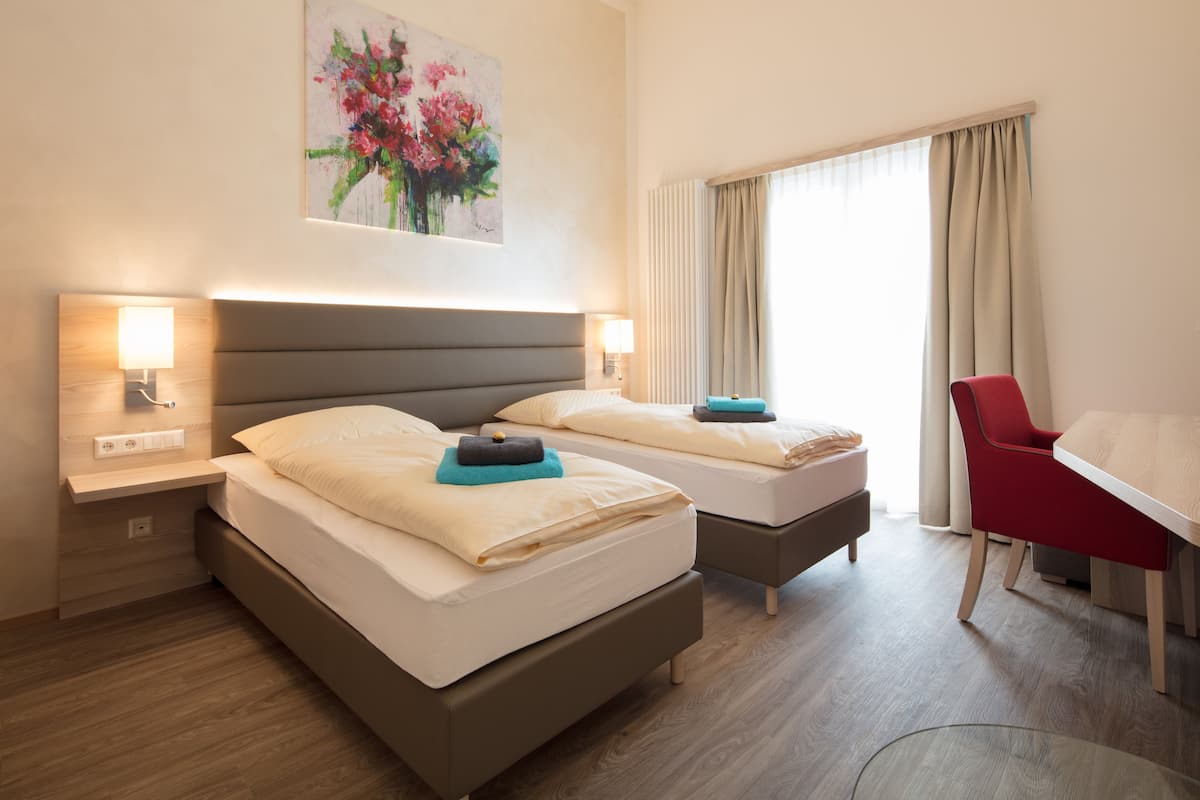 Una habitación de hotel con dos camas, un escritorio y una silla.