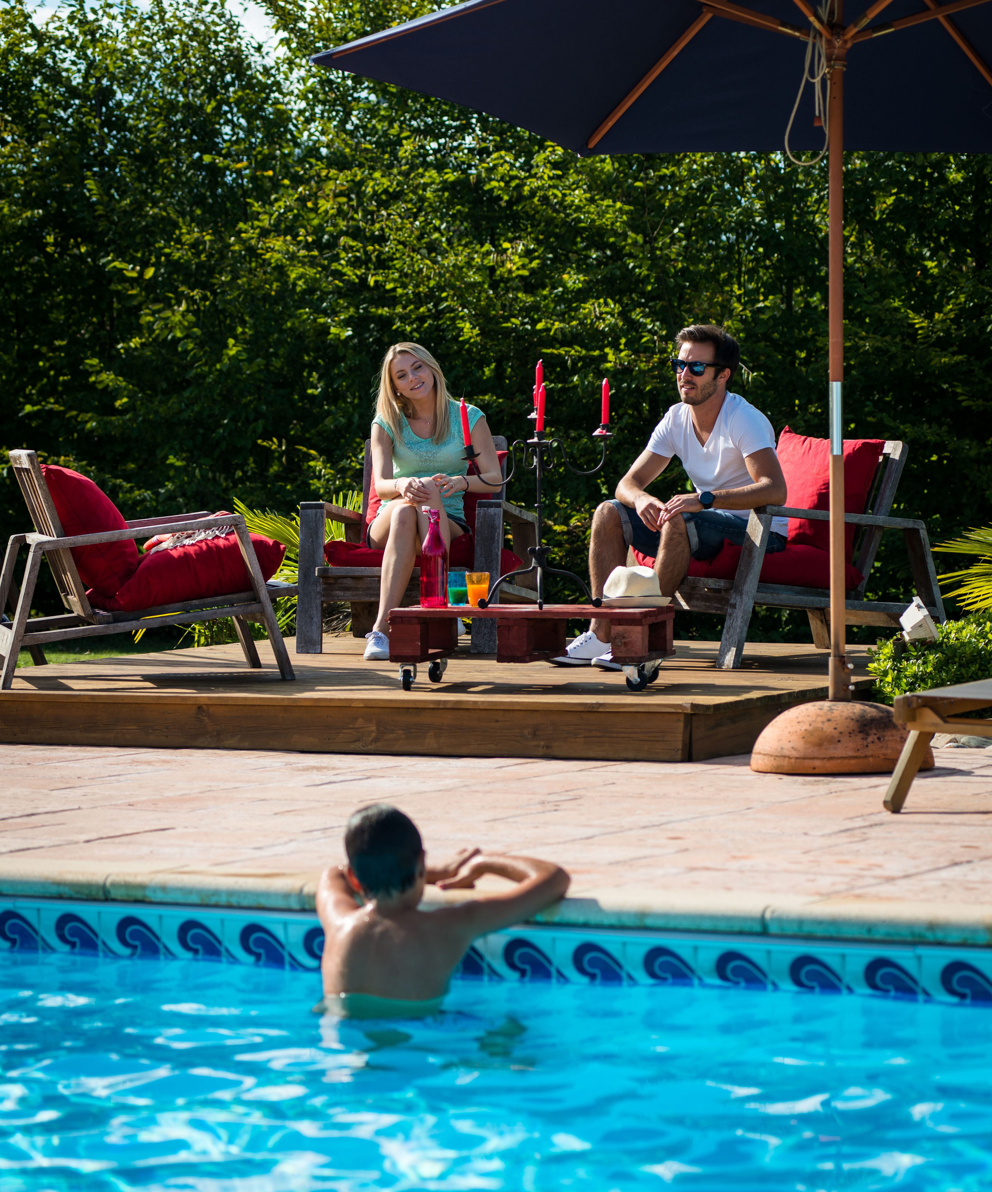 Et poolområde med liggestole, et bord med drikkevarer og en pool.