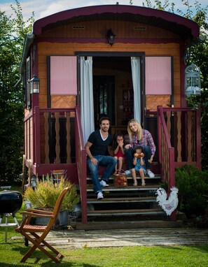 Une maison en bois avec un porche, un coq et un panier de pommes.